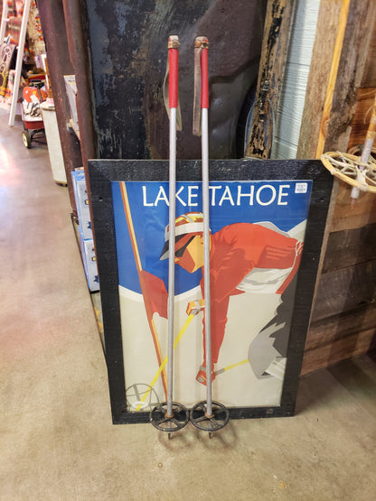 Vintage aluminum ski poles with red handles and leather straps