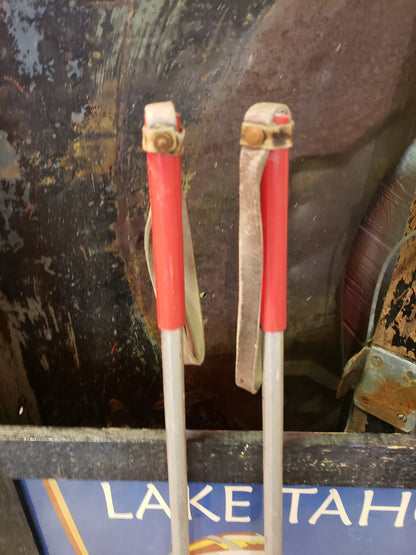 Vintage aluminum ski poles with red handles and leather straps