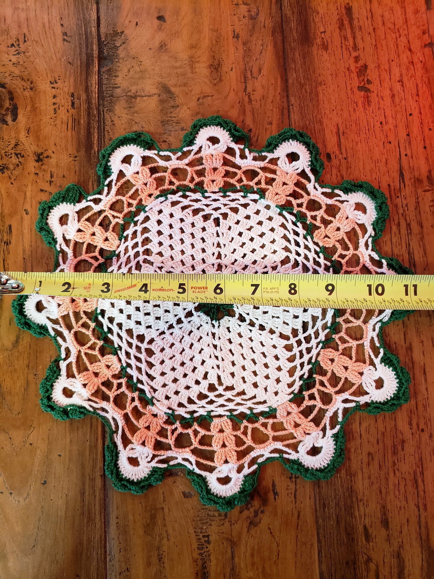 Round crochet doily in off white, peach and green